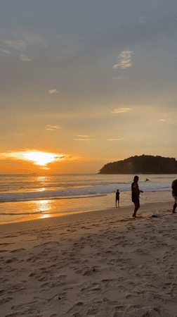 Sunset watchers gather at Thailand beach during golden hour