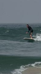 Surfer rides waves off Tel Aviv coast under gray skies