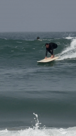 Surfer rides waves off Tel Aviv coast under gray skies