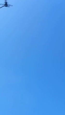 The video shows a clear blue sky. In the first few frames, a dark object, possibly a drone, is visible in the upper left corner. The object then disappears, and for the remainder of the video, only the sky is visible.