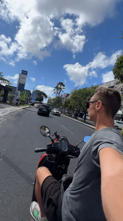 Man rides red scooter through Kuta streets