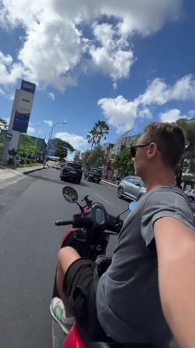 Man rides red scooter through Kuta streets