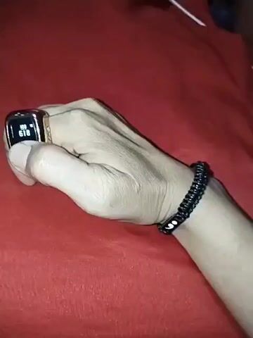 A hand with a black beaded bracelet on the wrist and a ring on the index finger is shown against a red surface. The ring has a digital display showing the number 619. The video then shows the number on the ring changing to 621, then to 623, then to 625, and finally to 627. The background is out of focus.