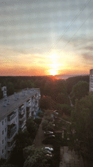 Urban sunset witnessed over apartment buildings and forest