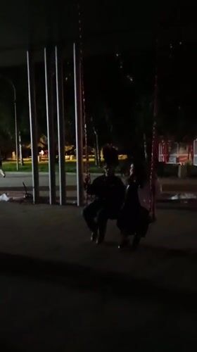 Evening out along a lit riverside promenade with sculptures and scooters