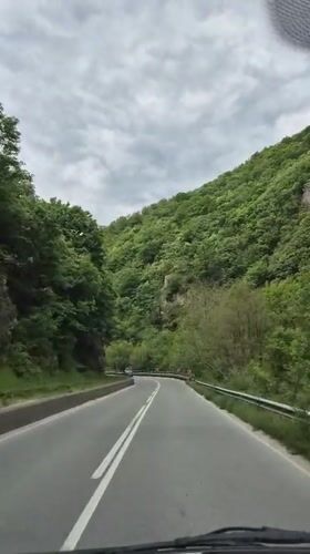 Vehicle travels curved forest road near Varvara, Bulgaria