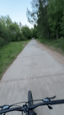 Cyclist rides tree-lined path in Noviy, Russia