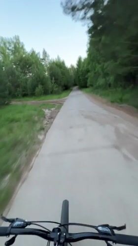 Cyclist rides tree-lined path in Noviy, Russia