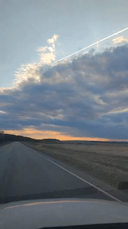 Vehicle travels rural road at dusk near Perevoznoe, Russia
