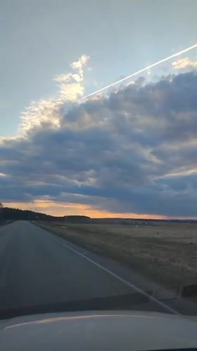 Vehicle travels rural road at dusk near Perevoznoe, Russia