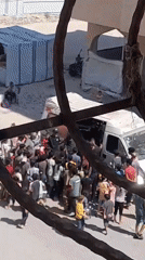 Large crowd gathers around white van in Khan Yunis street