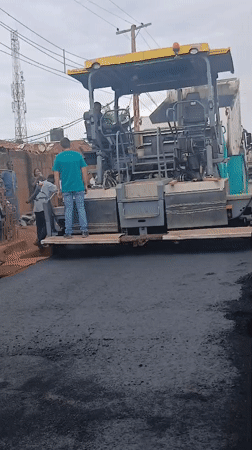 Road paving crew lays fresh asphalt through Yelwa, Nigeria