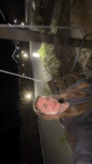 Woman enjoys evening swing session by illuminated lakeside in Russia