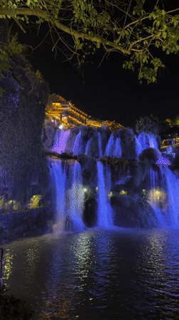 Purple-lit waterfall illuminates Furong Ancient Town at night