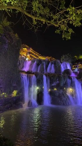 Purple-lit waterfall illuminates Furong Ancient Town at night