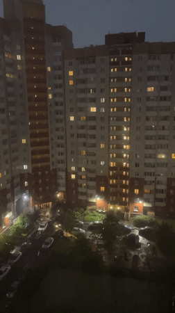 Apartment building at night, wet streets reflecting city lights
