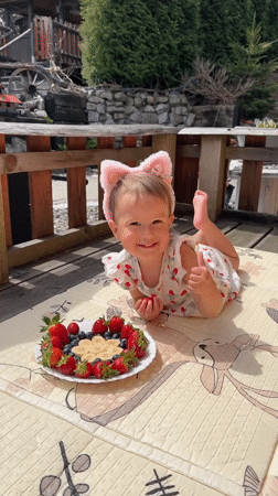 Toddler enjoys fruit snack on sunny deck in Wisła