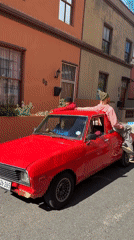 Red pickup with three men drives Cape Town street