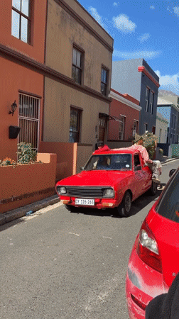 Red pickup with three men drives Cape Town street