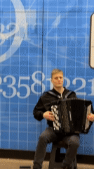 Accordion busker performs at Moscow metro station during afternoon rush