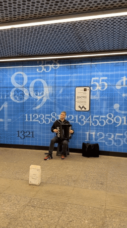 Accordion busker performs at Moscow metro station during afternoon rush