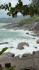 Rough seas crash against Patong's rocky coast under cloudy skies