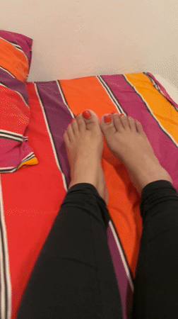 Person with red nail polish filmed on striped bed