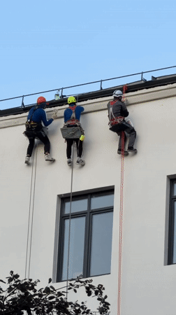 Rope-suspended workers clean or maintain a Moscow building facade.