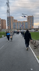 Pedestrians walk urban pathway past orange apartments in Russia