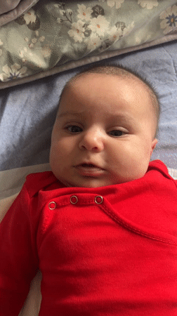 Baby in red onesie filmed on bed in Frankfurt