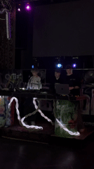 Three DJs perform on decorated stage with LED lighting