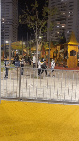 Children play with foam at nighttime playground in Kiryat Motzkin