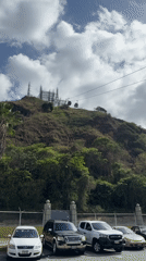 Cable cars operate above green hillside in Caracas