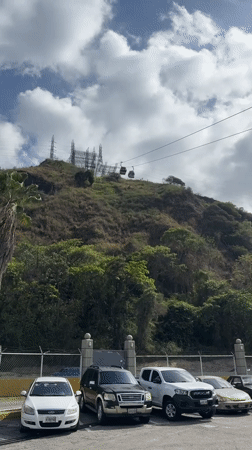 Cable cars operate above green hillside in Caracas