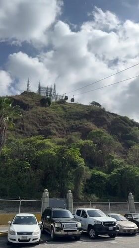 Cable cars operate above green hillside in Caracas