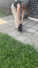 Woman plays with black and white puppy in Russian backyard