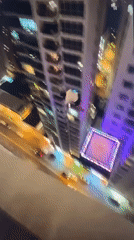 Person observed hanging from building edge at night