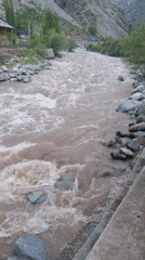 Swollen muddy river flows rapidly through Tajikistan mountains