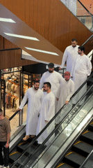 Shoppers in traditional dress ride escalators in Dubai mall