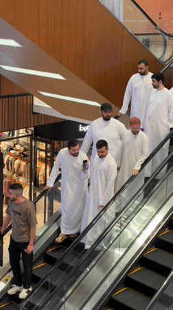 Shoppers in traditional dress ride escalators in Dubai mall