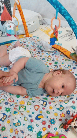 Baby enjoys tummy time on colorful playmat in Russia