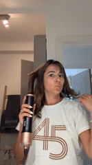 Woman styles hair with curling device in Cannes bathroom