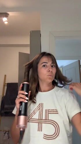 Woman styles hair with curling device in Cannes bathroom