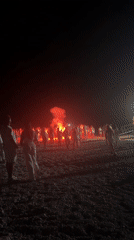 Bonfire and red flare light up a Greek beach night