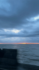 Car journey through coastal city during cloudy sunset conditions