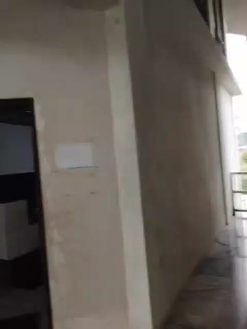 The video opens showing a green sign indicating a toilet and washroom. The camera then pans to the right, revealing a concrete staircase with marble steps. The walls appear unfinished, with visible patches of cement and paint. The staircase leads upwards into a brightly lit area. The video continues to show the staircase from different angles as the camera moves. There are no people visible in the video. The environment appears to be an indoor public space, possibly a building under construction or renovation, given the unfinished walls.