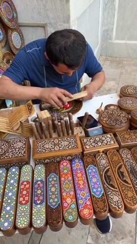 Traditional woodcarver works near historic Samarkand architecture