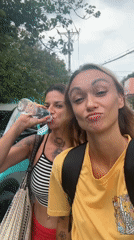 Two women pose for selfie video on Vietnam sidewalk
