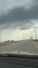 Heavy rain shaft looms over a Russian highway under stormy skies