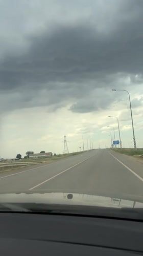 Heavy rain shaft looms over a Russian highway under stormy skies